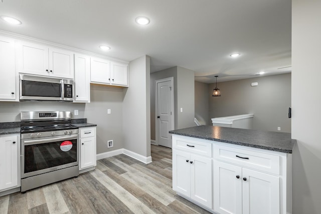 kitchen featuring stainless steel appliances, white cabinetry, kitchen peninsula, light hardwood / wood-style flooring, and hanging light fixtures