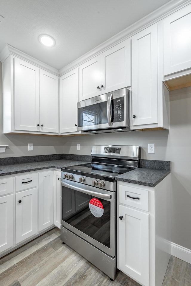 kitchen with stainless steel appliances, light wood-type flooring, and white cabinetry