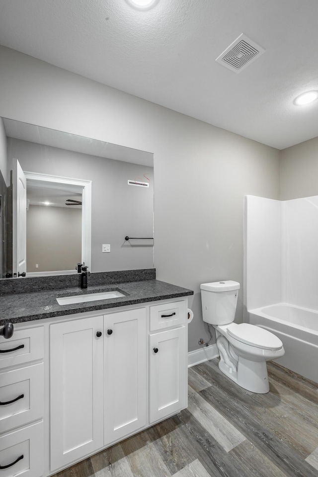 full bathroom with a textured ceiling, hardwood / wood-style flooring, vanity, and toilet