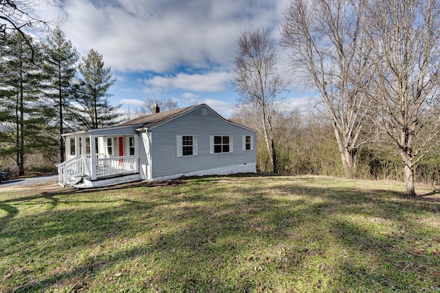 view of side of home featuring a lawn and covered porch