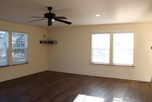 unfurnished room with a wealth of natural light, ceiling fan, and dark wood-type flooring