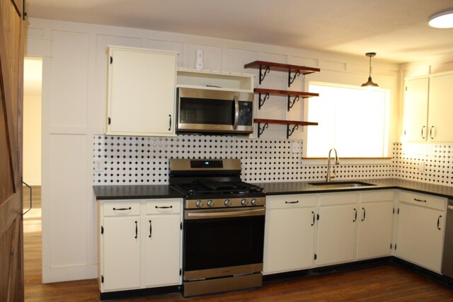 kitchen with decorative backsplash, stainless steel appliances, sink, white cabinets, and hanging light fixtures