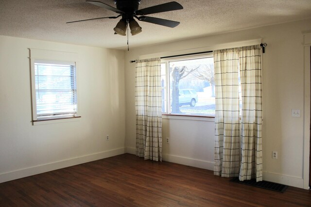 empty room featuring dark hardwood / wood-style floors, a healthy amount of sunlight, a textured ceiling, and ceiling fan