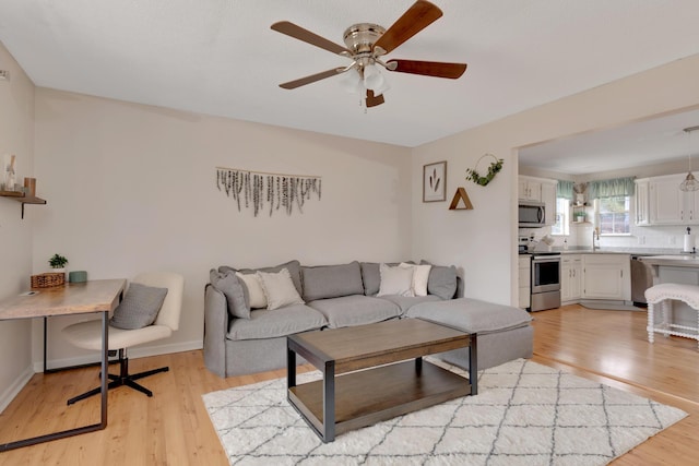 living room featuring ceiling fan, light hardwood / wood-style floors, and sink