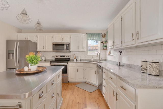 kitchen with appliances with stainless steel finishes, pendant lighting, white cabinets, and sink