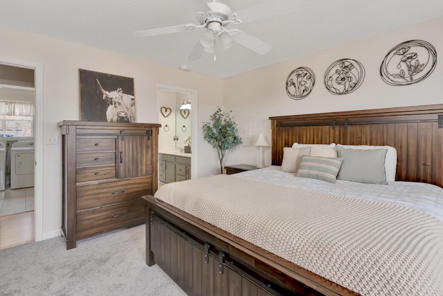 bedroom featuring ceiling fan, light colored carpet, ensuite bath, washing machine and dryer, and a textured ceiling