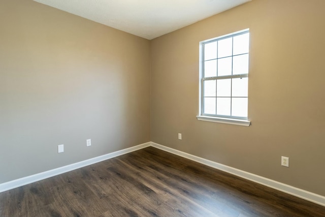 spare room with a wealth of natural light and dark hardwood / wood-style flooring