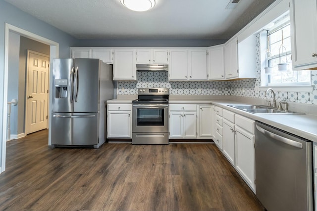 kitchen featuring sink, dark hardwood / wood-style flooring, decorative backsplash, white cabinets, and appliances with stainless steel finishes