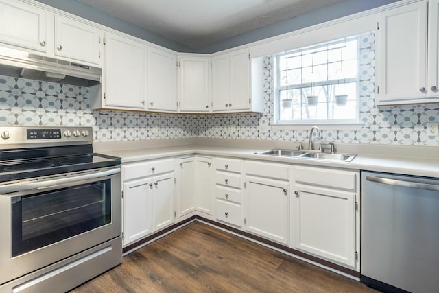 kitchen with appliances with stainless steel finishes, tasteful backsplash, dark wood-type flooring, sink, and white cabinets