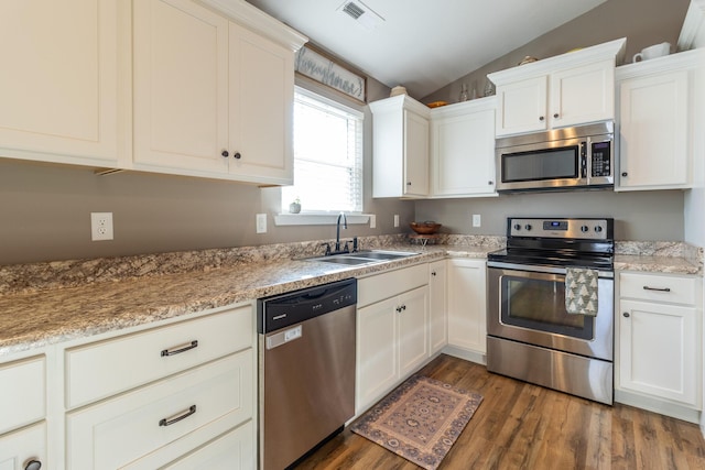 kitchen featuring stainless steel appliances, white cabinetry, lofted ceiling, and sink