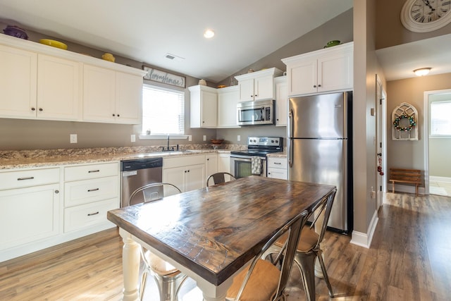 kitchen featuring white cabinets, sink, vaulted ceiling, plenty of natural light, and stainless steel appliances