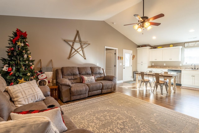 living room featuring ceiling fan, light hardwood / wood-style floors, sink, and vaulted ceiling