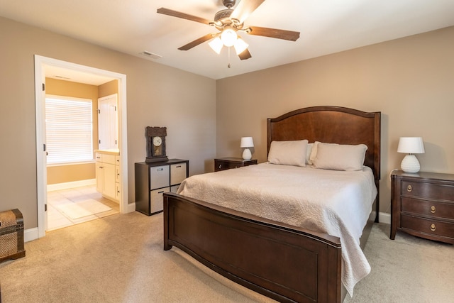 carpeted bedroom with ensuite bathroom and ceiling fan