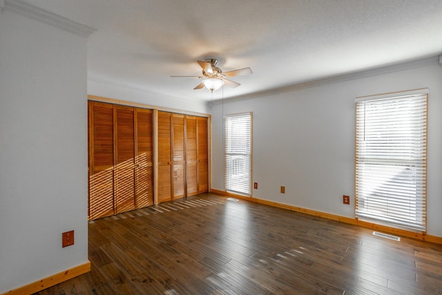 unfurnished bedroom featuring ceiling fan, multiple windows, and ornamental molding