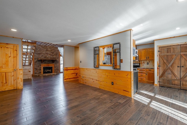 unfurnished living room with ornamental molding, dark hardwood / wood-style flooring, and a stone fireplace