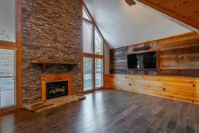 unfurnished living room with wood-type flooring, wooden walls, and high vaulted ceiling