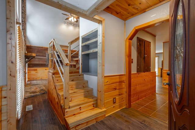 stairway with ceiling fan, wood ceiling, hardwood / wood-style floors, and wooden walls