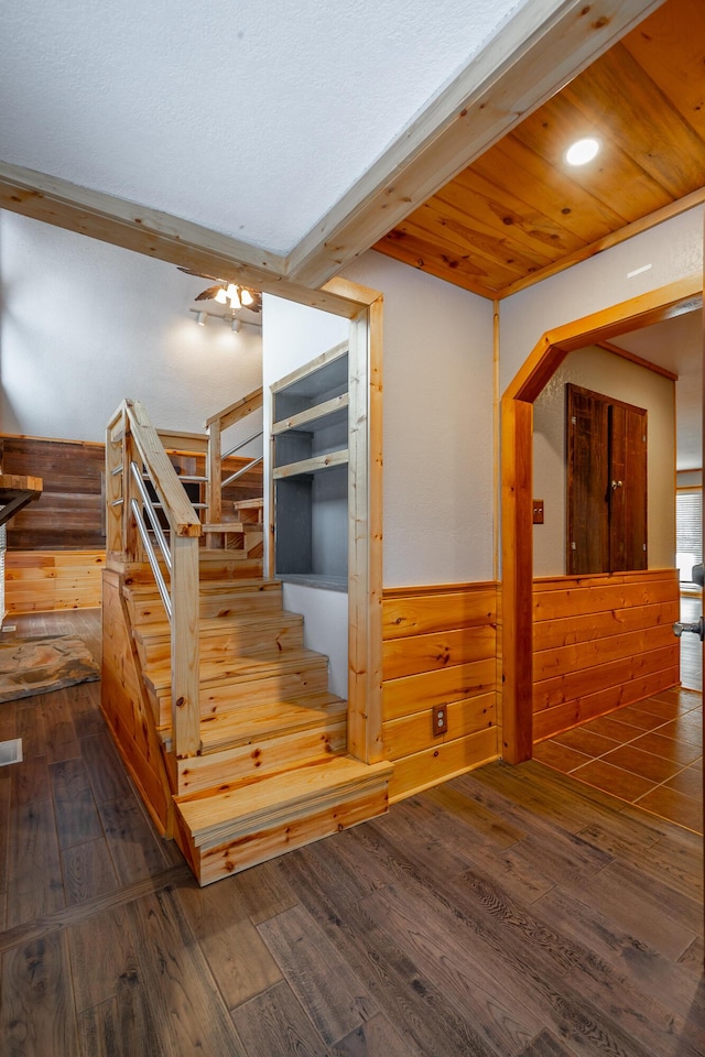 staircase with hardwood / wood-style flooring, wood walls, and beamed ceiling