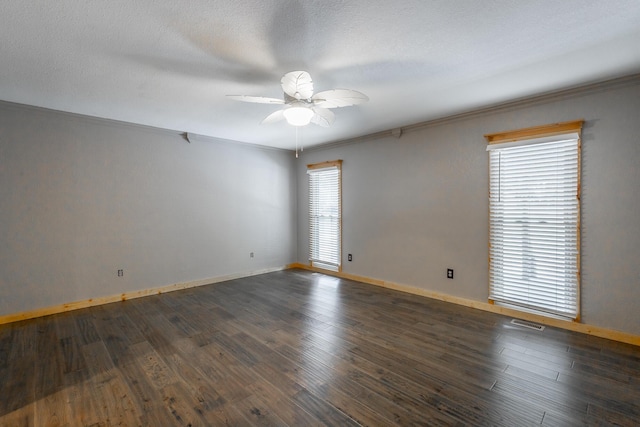 unfurnished room featuring dark wood-type flooring, ceiling fan, ornamental molding, and a healthy amount of sunlight