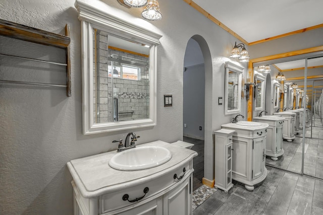 bathroom featuring an enclosed shower, vanity, ornamental molding, and a chandelier