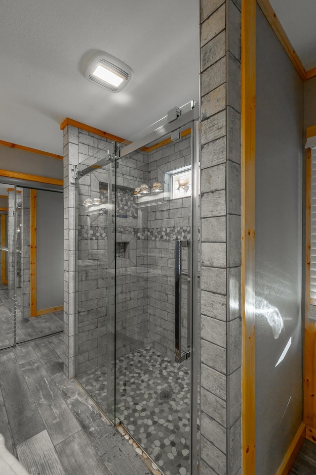 bathroom with a shower with shower door and ornamental molding