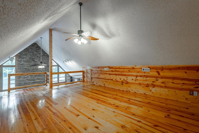 additional living space featuring ceiling fan, hardwood / wood-style floors, a textured ceiling, and vaulted ceiling