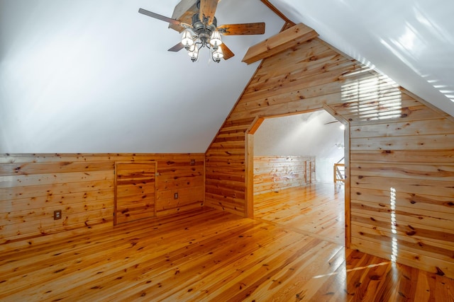 additional living space with lofted ceiling, wooden walls, and hardwood / wood-style flooring