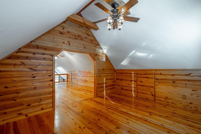 bonus room featuring lofted ceiling, wood-type flooring, and wooden walls