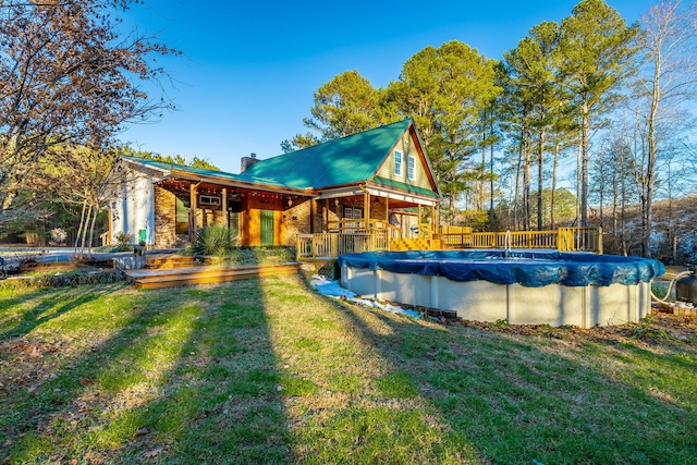 rear view of property featuring a swimming pool side deck and a yard