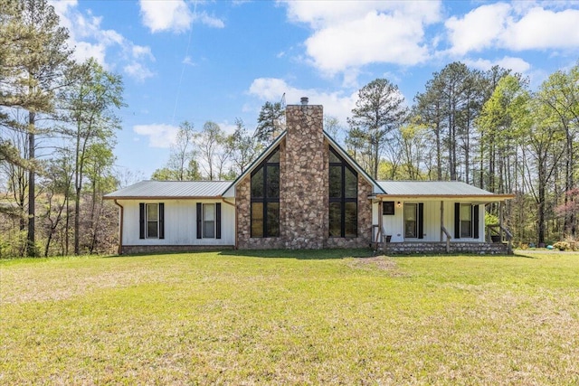 view of front facade featuring a chimney, metal roof, and a front lawn