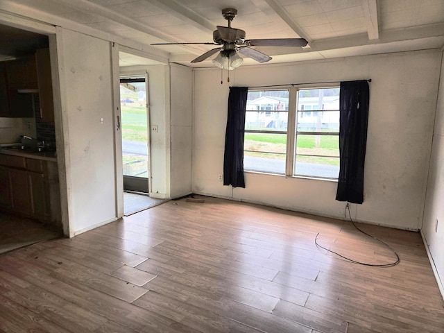 empty room featuring beamed ceiling, light hardwood / wood-style floors, ceiling fan, and sink