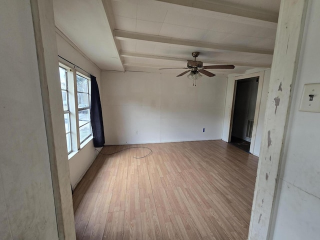 empty room featuring beam ceiling, ceiling fan, and light wood-type flooring