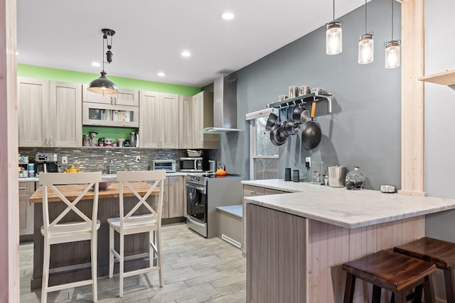 kitchen with backsplash, hanging light fixtures, wall chimney exhaust hood, a kitchen bar, and stainless steel appliances