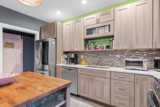 kitchen featuring butcher block counters, sink, stainless steel appliances, a barn door, and backsplash