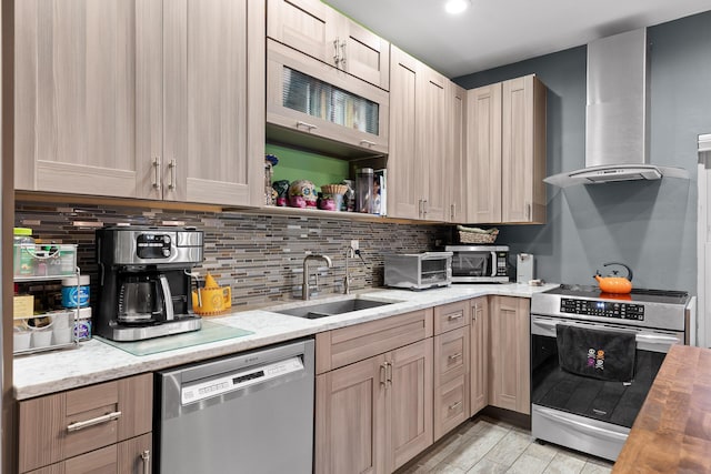 kitchen with butcher block counters, sink, wall chimney exhaust hood, light brown cabinets, and appliances with stainless steel finishes