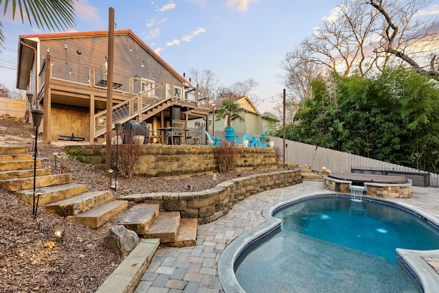 pool at dusk with an in ground hot tub and a wooden deck