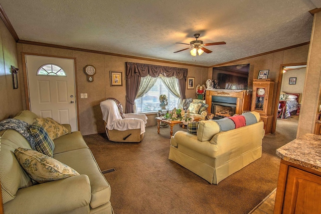 living room with ceiling fan, crown molding, dark carpet, and a textured ceiling