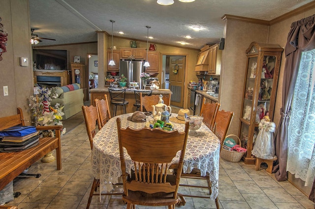 dining area featuring a textured ceiling, vaulted ceiling, ceiling fan, and ornamental molding