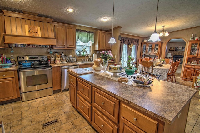 kitchen featuring appliances with stainless steel finishes, a textured ceiling, sink, a center island, and hanging light fixtures