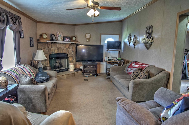 living room with carpet, ceiling fan, ornamental molding, a fireplace, and a textured ceiling