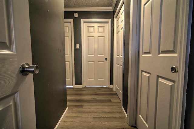 hallway with dark wood-type flooring, crown molding, and a textured ceiling