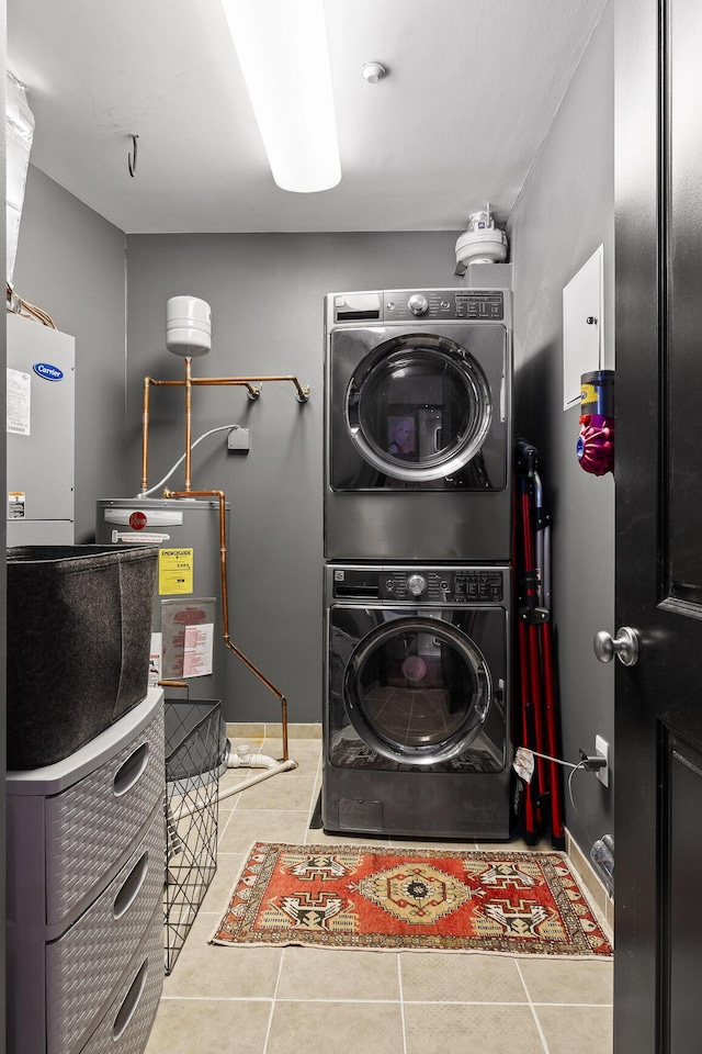 clothes washing area with light tile patterned flooring, stacked washer / dryer, and water heater