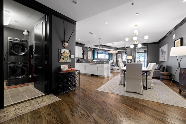 dining space featuring a chandelier, plenty of natural light, stacked washing maching and dryer, and wood-type flooring