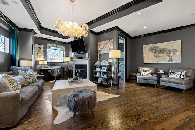 living room with dark hardwood / wood-style flooring, crown molding, a fireplace, and an inviting chandelier