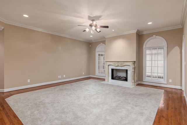 unfurnished living room featuring a high end fireplace, wood-type flooring, ceiling fan, and ornamental molding