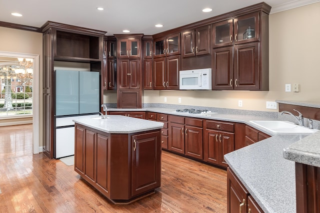 kitchen with dark brown cabinetry, white appliances, sink, and light wood-type flooring