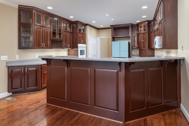 kitchen featuring a kitchen bar, kitchen peninsula, and white appliances