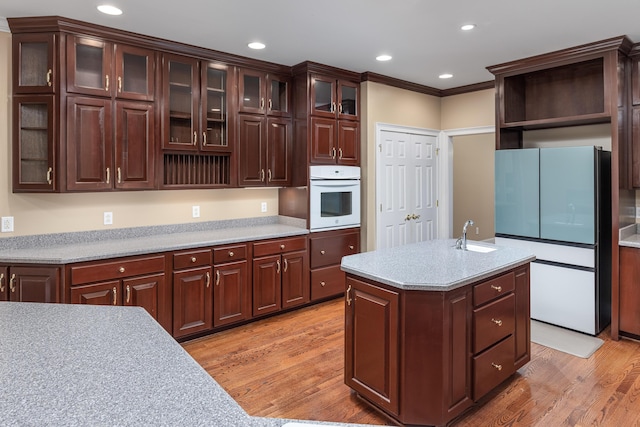 kitchen with dark brown cabinets, white appliances, light hardwood / wood-style flooring, and ornamental molding