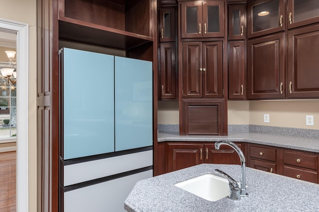 kitchen with light stone countertops, dark brown cabinetry, and sink