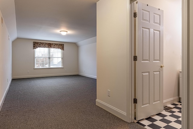 additional living space with dark colored carpet and vaulted ceiling